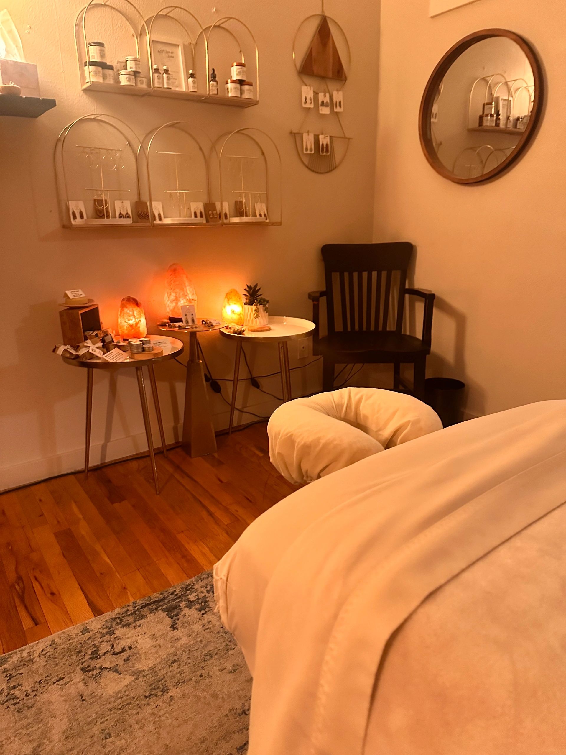 Candlelit treatment room at Idylwild Therapy with warm salt lamps, a draped massage table, and wood floors